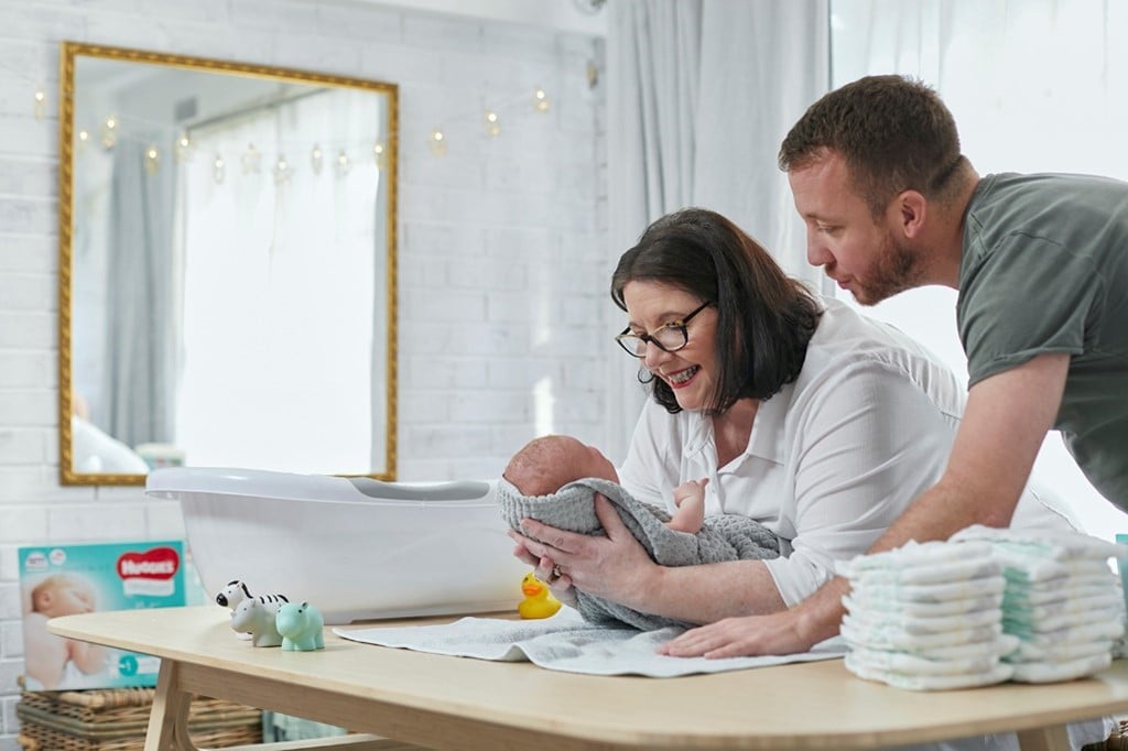 Newborn baby wearing Huggies nappies, held by Midwife Cath and dad